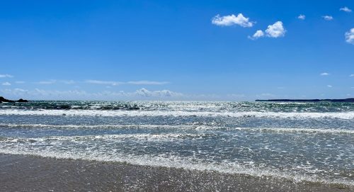 Sunlight glittering on waves on a sandy beach